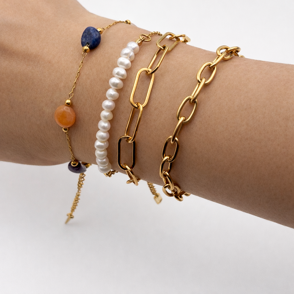 Gold bracelets with various designs on a wrist against a white background