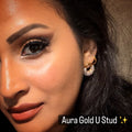 Close-up of a woman wearing gold earrings with 'Aura Gold U Stud' text.
