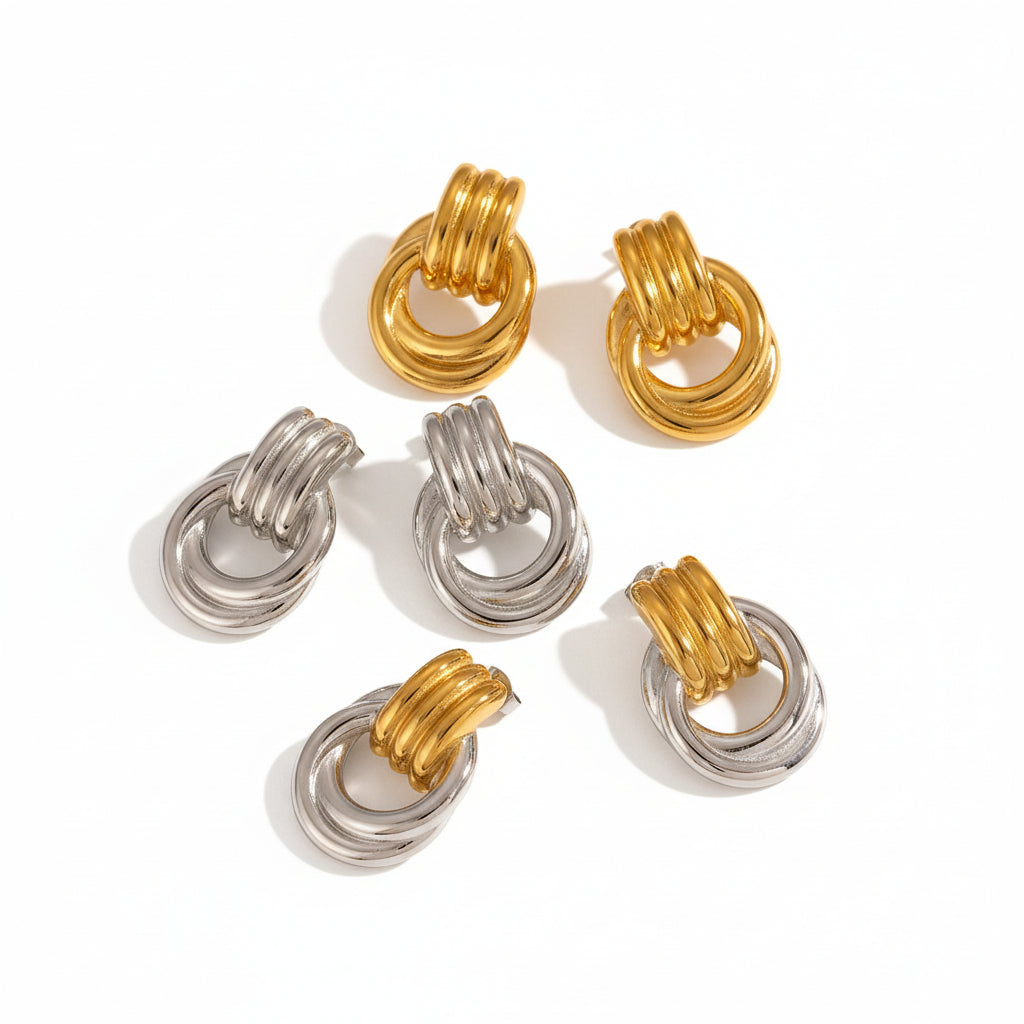 Gold and silver hoop earrings on a textured beige surface