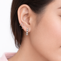 Close-up of a person wearing silver hoop earrings with a blurred background