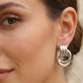 Close-up of a woman wearing silver hoop earrings with a neutral background