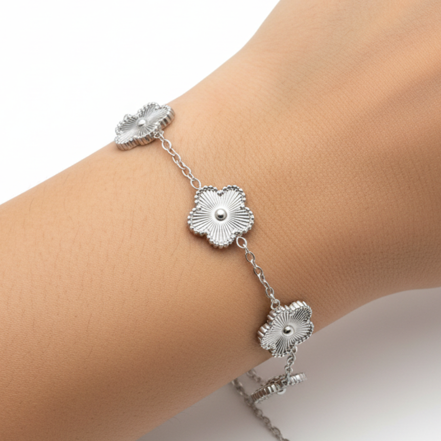 Silver bracelet with floral designs on a wrist against a white background