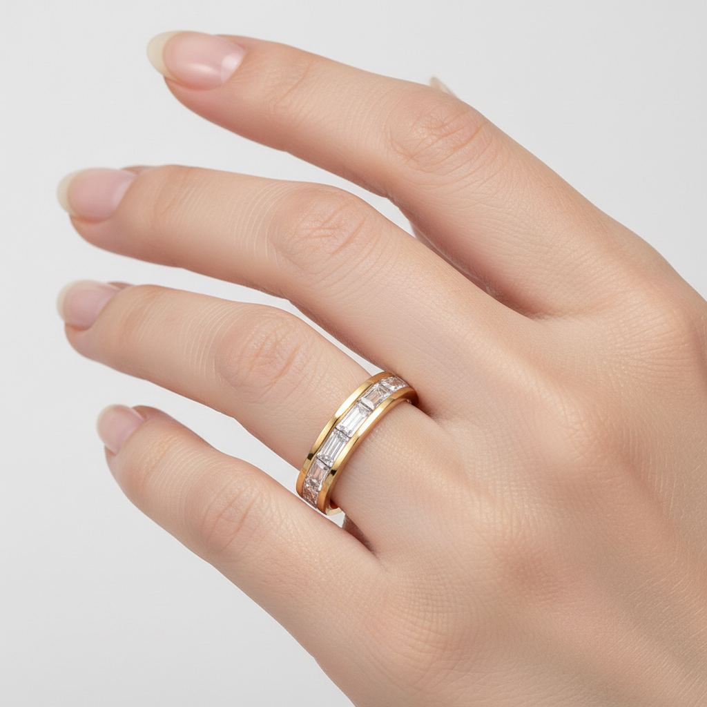 Gold ring with diamonds on a hand against a light gray background