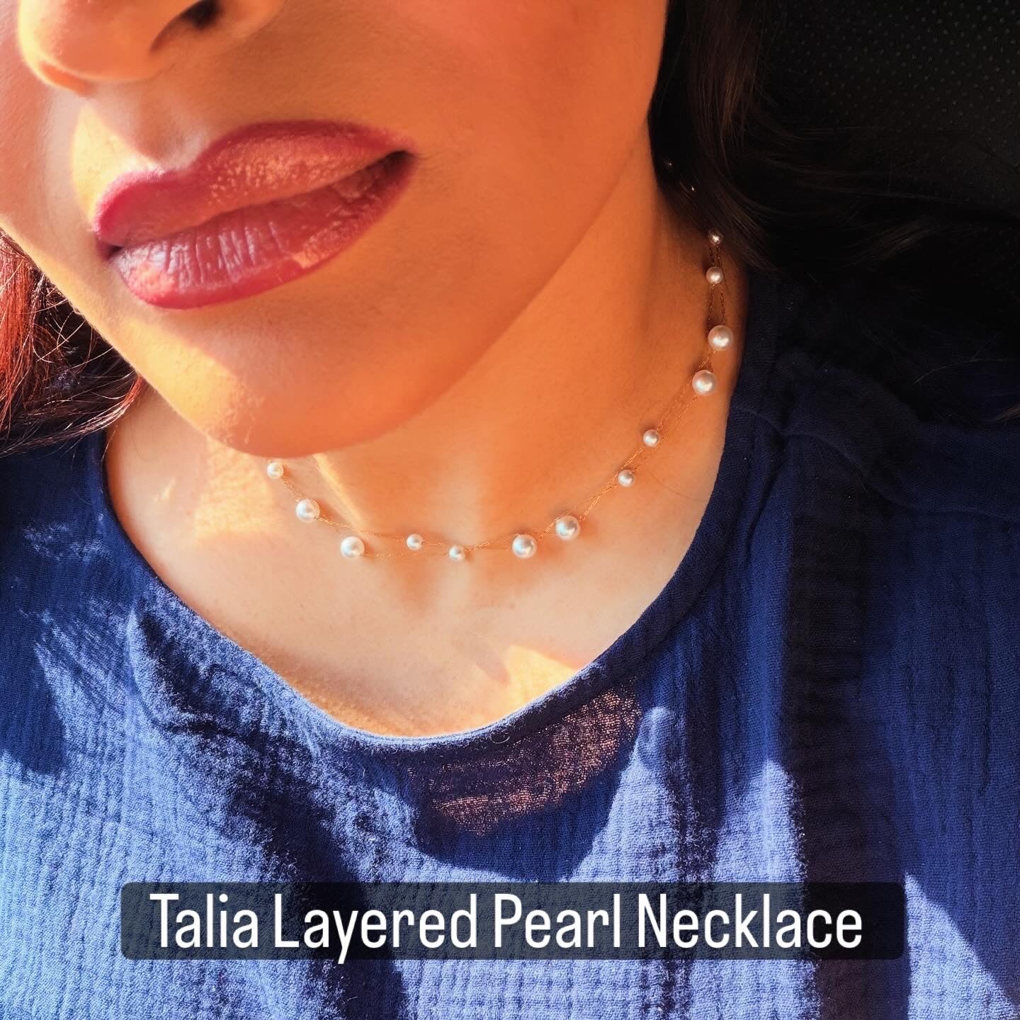 Woman wearing a layered pearl necklace with a blue top.