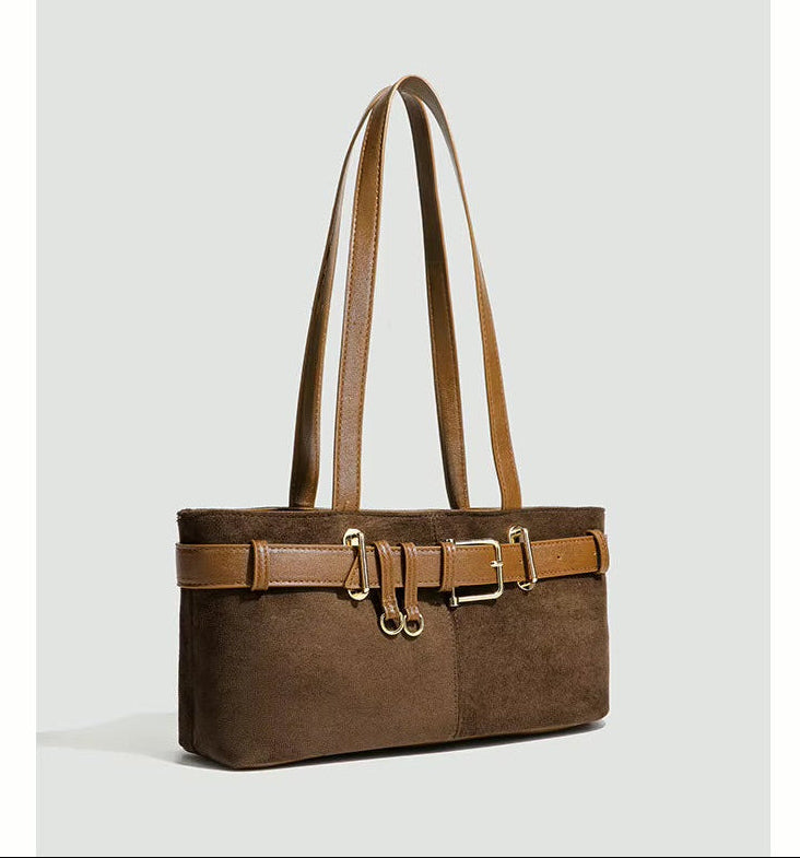 Brown suede handbag with gold accents on a light gray background