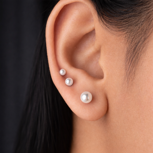 Close-up of an ear wearing pearl earrings with a blurred background