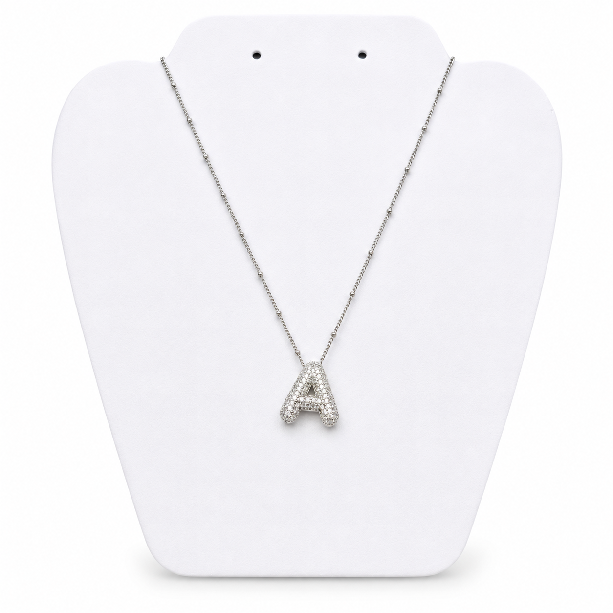 A silver initial necklace featuring the letter 'A' paved with small clear stones, displayed on a white jewelry bust.