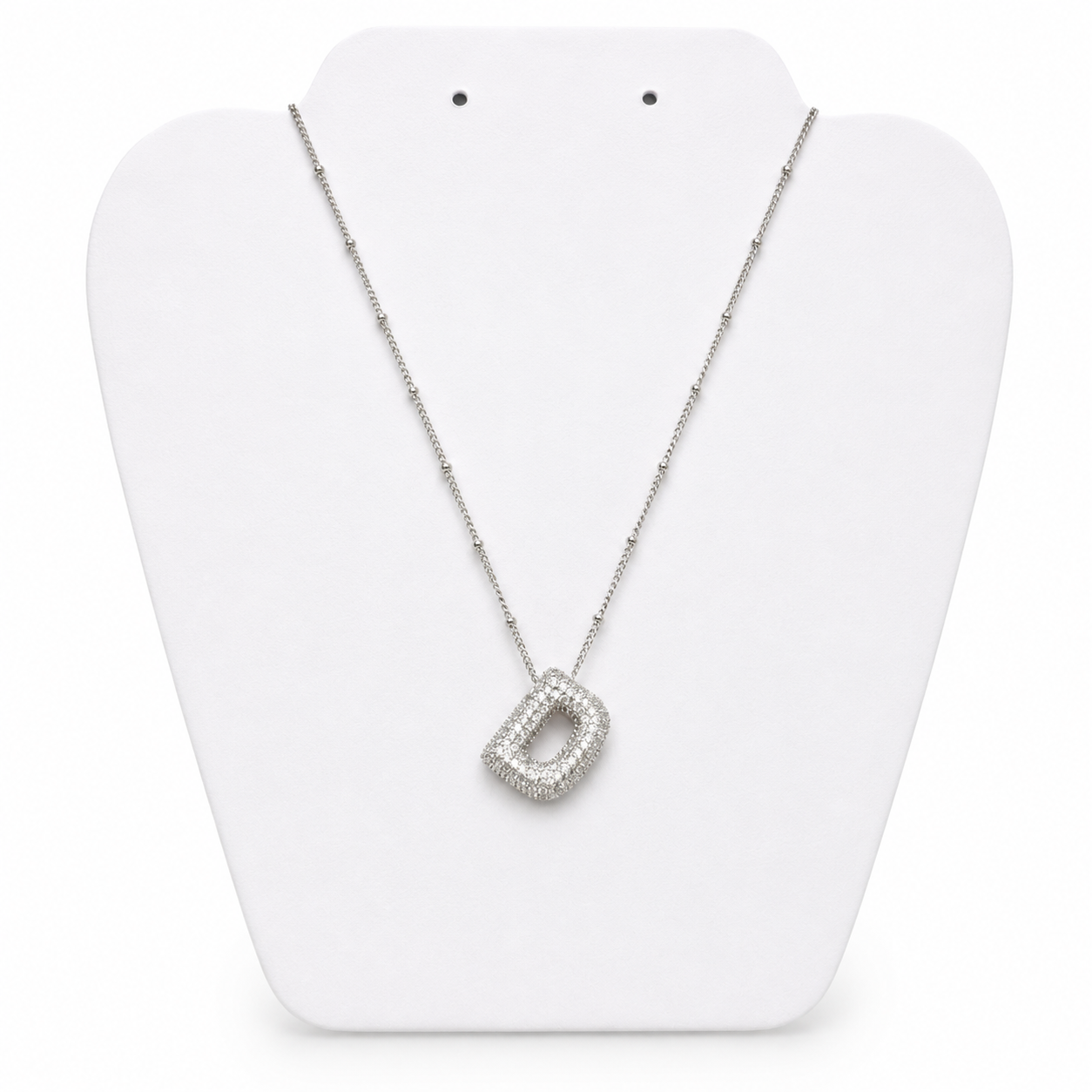 A silver-toned necklace with a geometric open pendant encrusted with clear stones, displayed on a white jewelry bust against a white background.